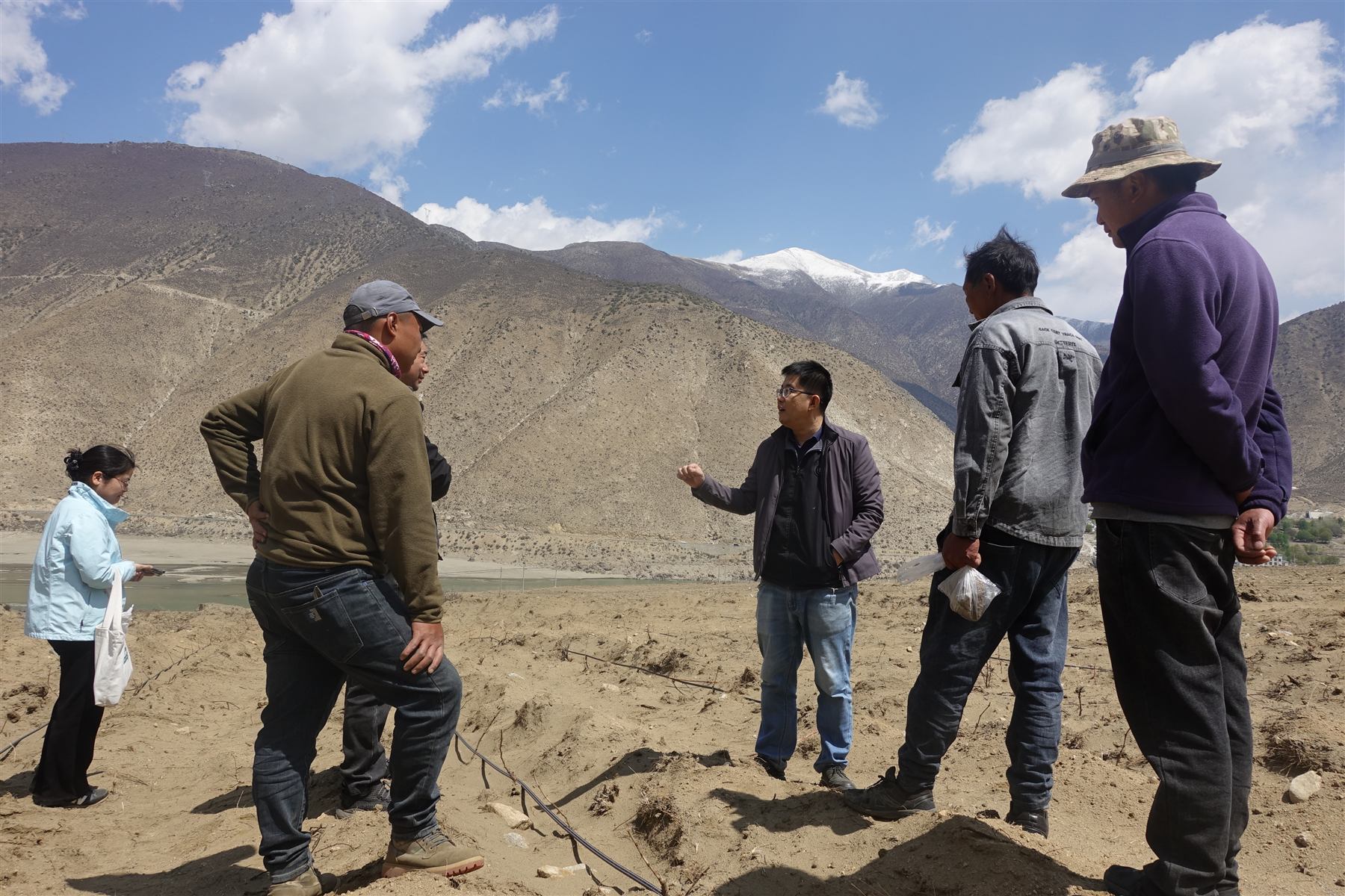 The founding team standing in an early vineyard plot with snow mountains beyond